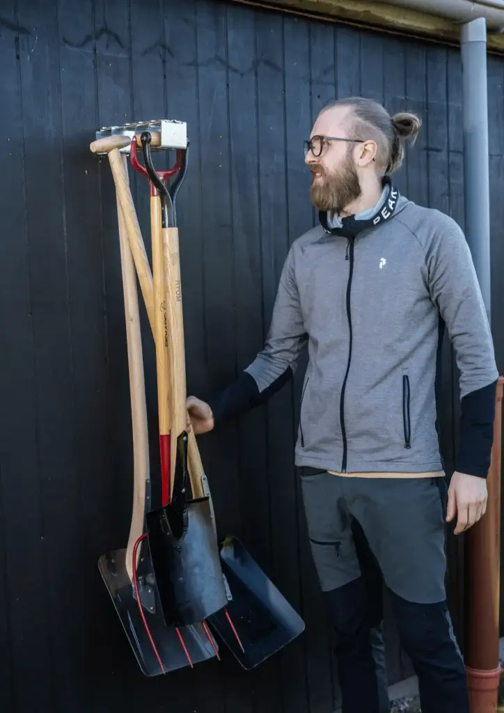 Anders kigger på de haveredskaber han lige har hængt op på siden af kolonihavehuset.
