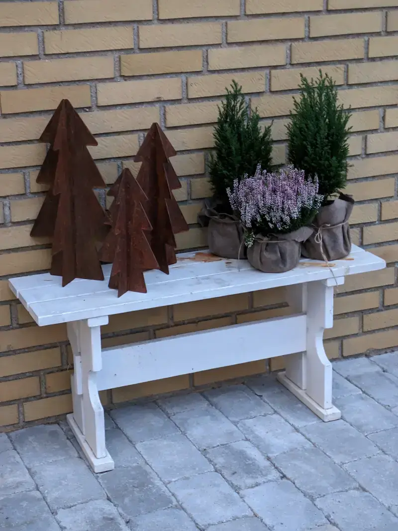 Smukke træer/juletræer i cortenstål på en bænk med blomster