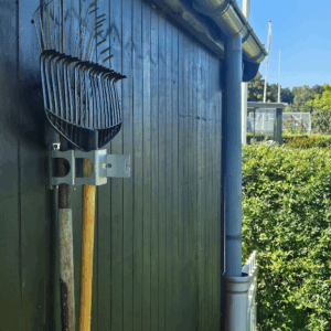 Et redskabsophæng i metal på en sort trævæg der holder 2 redskab i med hovedet opad. Ophænget har individuelle holdere til hvert redskab. Lukket