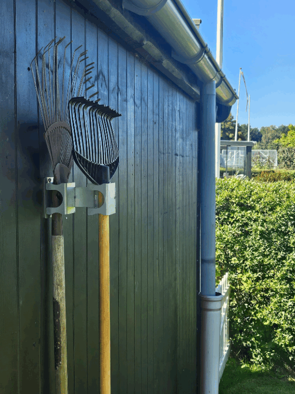 Viting-redskabsophæng-2-4 Et redskabsophæng i metal på en sort trævæg der holder 2 redskab i med hovedet opad. Ophænget har individuelle holdere til hvert redskab hvor den ene holder er åbnet.