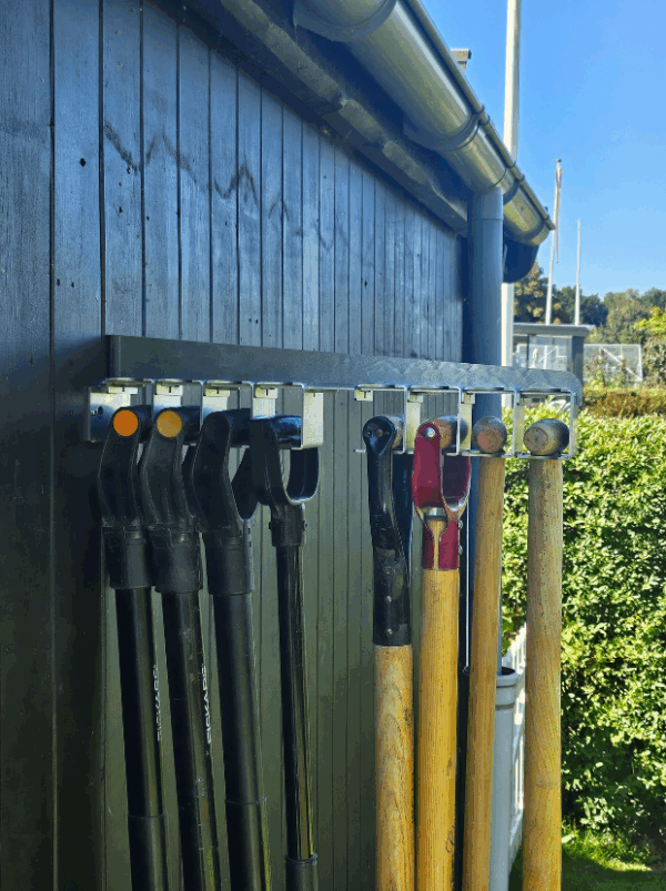 Viting-redskabsophæng-8-2 Et redskabsophæng i metal på en sort trævæg der holder 8 redskaber i deres greb. Ophænget har individuelle holdere til hvert redskab hvor den ene holder er åben. Alle 8 er med D greb.